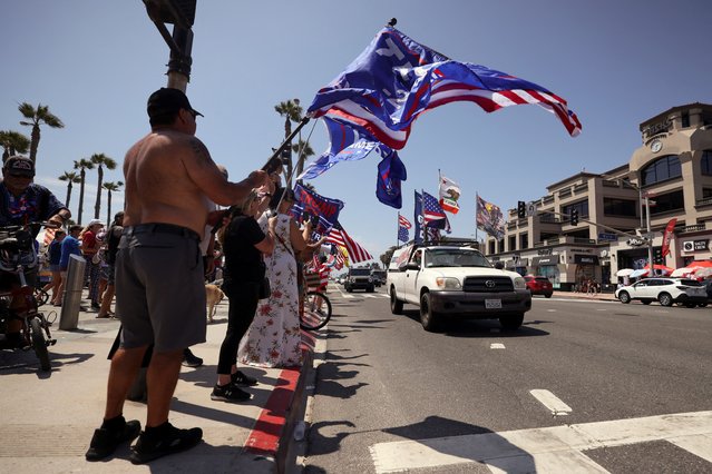 Pro-Trump supporters cheer as a car drives with American and pro-Trump flags during a demonstration in support of former U.S. President Donald Trump who was shot the previous day in an assassination attempt during a rally in Pennsylvania, in Huntington Beach, California, U.S. July 14, 2024. (Photo by Etienne Laurent/Reuters)