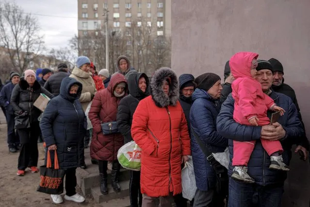 People line up for food handed out by volunteers at a humanitarian aid distribution point, as Russia's attack on Ukraine continues, in Kharkiv, Ukraine, March 28, 2022. (Photo by Rodrigo Abd/AP Photo)