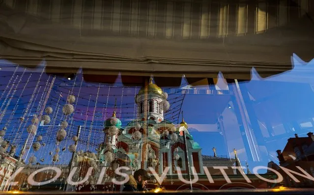 A church is reflected in a window of a closed Louis Vuitton boutique in the GUM department store in Moscow, Russia on March 15, 2022. (Photo by Evgenia Novozhenina/Reuters)