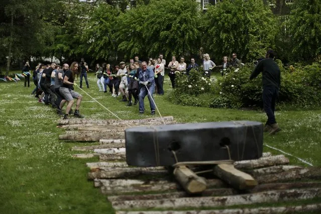 Volunteers, many of whom were undergraduate archeology students, take part in an attempt using only people power to move a one tonne block strapped to a neolithic-style wooden sledge, in Gordon Square, London, Monday, May 23, 2016. The part experiment, part experience Monday was an investigation of the technology used to move large stones to build prehistoric monuments such as Stonehenge. (Photo by Matt Dunham/AP Photo)