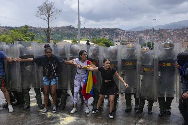 Residents try to block a street to protest the official results the day after the presidential election as National Guards work to remove them in Caracas, Venezuela, Monday, July 29, 2024. (Photo by Fernando Vergara/AP Photo)