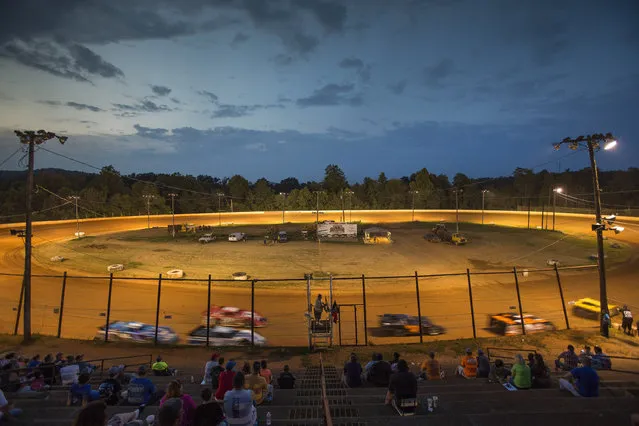 In this July 17, 2015 photo, drivers speed around the red clay, D-shaped Ponderosa Speedway at dusk in Junction City, Ky. At the Ponderosa Speedway, a race track made of red clay and nestled in the small hills of central Kentucky, spectators can be sure they will take a little piece of the track with them at the end of the night. (Photo by David Stephenson/AP Photo)