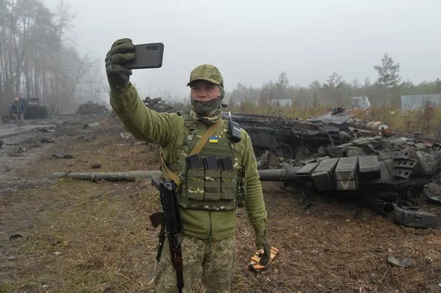 A Ukrainian service member takes a selfie in a front of a destroyed Russian T-72 tank, as Russia?s attack on Ukraine continues, in the village of Dmytrivka in Kyiv region, Ukraine on April 1, 2022. (Photo by Oleksandr Klymenko/Reuters)