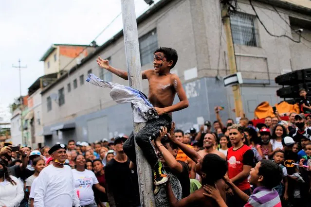 Children participate in a greasy pole game during the traditional burning of Judas, as part of the Holy Week celebrations in Caracas, Venezuela on April 17, 2022. (Photo by Leonardo Fernandez Viloria/Reuters)
