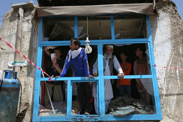 Afghans look out of a damaged shop after a suicide attack in Kabul, Afghanistan, Monday, May 4, 2015. An Afghan official says a suicide bomber struck a minibus carrying government employees in Kabul, killing at least one person and wounding more than a dozen. Interior Ministry spokesman Sediq Sediqqi says the minibus was carrying employees of the attorney general's office when it was attacked early Monday. (Photo by Rahmat Gul/AP Photo)