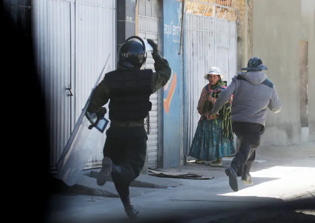 A demonstrator runs away from a riot policeman during a protest by workers from ENATEX, a state-run textile company, in La Paz, Bolivia, May 31, 2016. Hundreds of workers were dismissed from their jobs because of the closure of ENATEX. (Photo by David Mercado/Reuters)