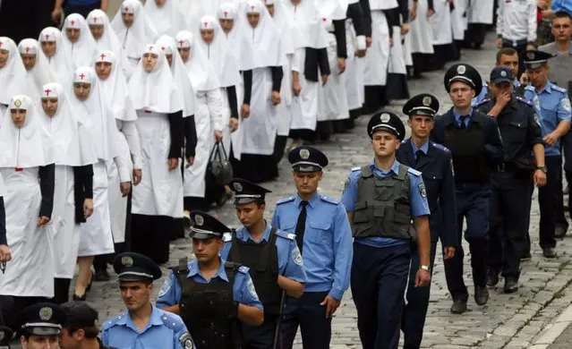 Police officers accompany nuns taking part in a procession marking the 1,000th anniversary of the death of Vladimir the Great in Kiev, Ukraine, July 27, 2015. (Photo by Valentyn Ogirenko/Reuters)