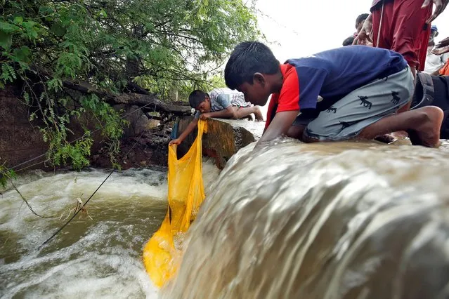 Boys try to catch fish in an overflowing drain after heavy rains in Chennai, India, December 2, 2019. (Photo by P. Ravikumar/Reuters)