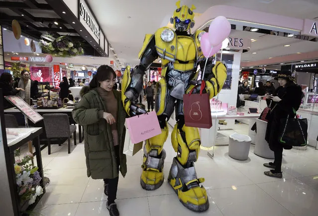 In this Thursday, February 14, 2019, photo, a Transformer's Bumblebee mascot helps a woman carries paper bags at a shopping mall in Handan in north China's Hebei province. U.S. and Chinese envoys are holding a second day of trade talks after the top economic adviser to President Donald Trump said he has yet to decide whether to go ahead with a March 2 tariff increase on imports from China. (Photo by Chinatopix via AP Photo)