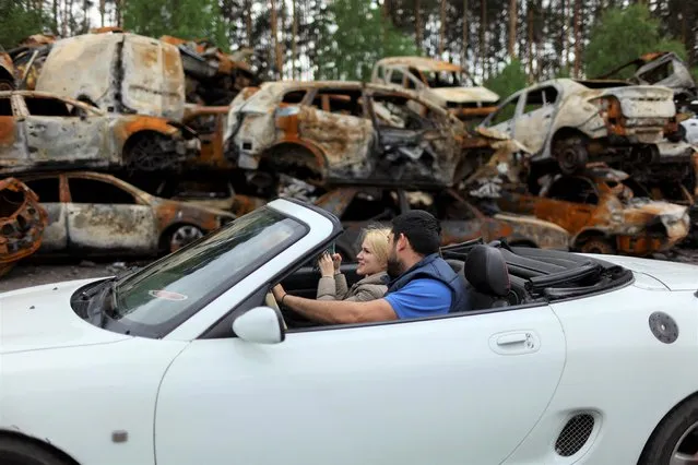 A couple sit in a car, at a holding point for civilian vehicles damaged and destroyed by Russian attacks, as the Russian invasion of Ukraine continues, in Bucha, Ukraine, May 14, 2022. (Photo by Ahmed Jadallah/Reuters)