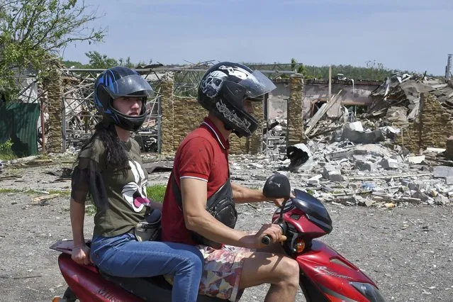 People ride a bike past a building damaged by an overnight missile strike in Sloviansk, Ukraine, Wednesday, June 1, 2022. (Photo by Andriy Andriyenko/AP Photo)