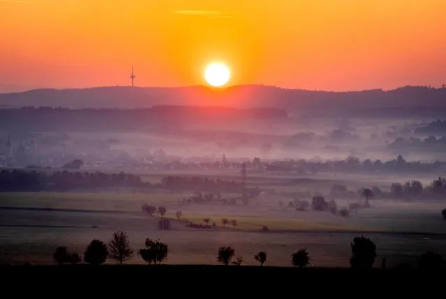 The sun rises on the horizon on a misty Thursday morning, April 28, 2022, outside Frankfurt, Germany. (Photo by Michael Probst/AP Photo)