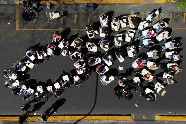 In this aerial view students take a class in the street outside the faculty of philosophy and letters of the University of Buenos Aires (UBA) in Buenos Aires on October 16, 2024. Students from Argentina's public universities escalated the conflict against Javier Milei's government's budget cuts on Wednesday, with dozens of public classes, takeovers of faculties and a torch march planned for the evening, as a prelude to a federal mobilisation that has yet to be scheduled. (Photo by Juan Mabromata/AFP Photo)