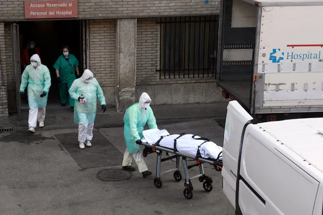 A health worker carries a body on a stretcher outside Gregorio Maranon hospital in Madrid on March 25, 2020. Spain joined Italy today in seeing its death toll from the coronavirus epidemic surpass that of China, as more than a billion Indians joined a lockdown that has confined a third of humanity. (Photo by Oscar Del Pozo/AFP Photo)