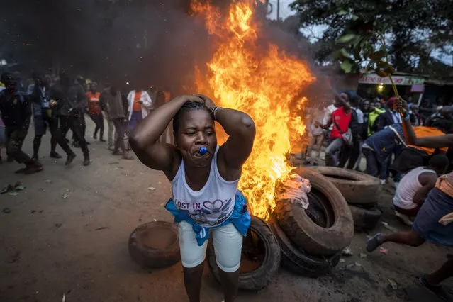 A supporter of presidential candidate Raila Odinga blows a whistle as she protests next to a roadblock of burning tires in the Kibera neighborhood of Nairobi, Kenya Monday, August 15, 2022. After last-minute chaos that could foreshadow a court challenge, Kenya's electoral commission chairman has declared Deputy President William Ruto the winner of the close presidential election over five-time contender Raila Odinga. (Photo by Ben Curtis/AP Photo)