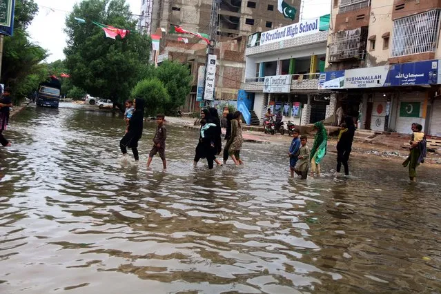 People make their ways through a flooded area following heavy rains in Hyderabad, Pakistan, 25 August 2022. Flash floods caused by heavy monsoon rains have killed 830 people, including 313 children, across Pakistan in the last two months, according to the National Disaster Management Authority (NDMA). More than three million people have been affected by the floods, with over 161,000 still living in relief camps since the monsoon began on June 14, government data showed. (Photo by Nadeem Khawar/EPA/EFE)