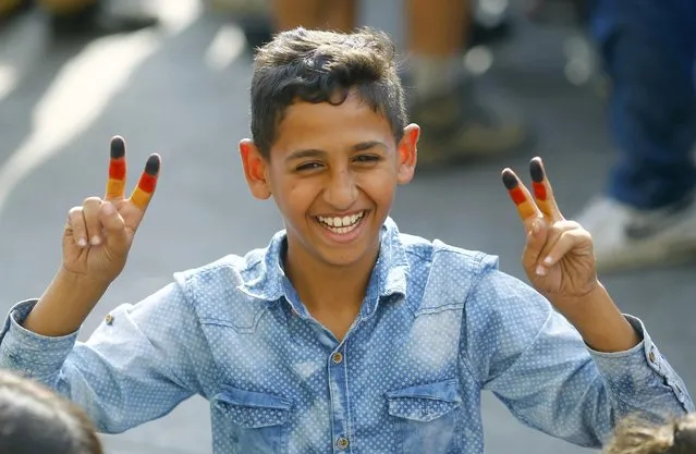 A young migrant boy with his fingers painted in the colours of the German national flag, smiles outside Keleti train station in Budapest, Hungary, September 3, 2015. (Photo by Leonhard Foeger/Reuters)