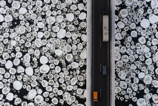Vehicles travel on a road past the ice-covered Vistula River near Kiezmark, Poland. (Photo by Kacper Kowalski/Panos Pictures)