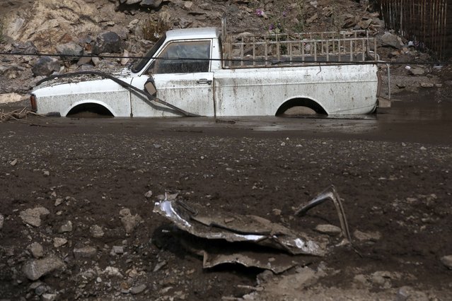 A car is stuck in mud after flash flooding at Imamzadeh Davood village in the northwestern part of Tehran, Iran, Thursday, July 28, 2022. (Photo by Vahid Salemi/AP Photo)