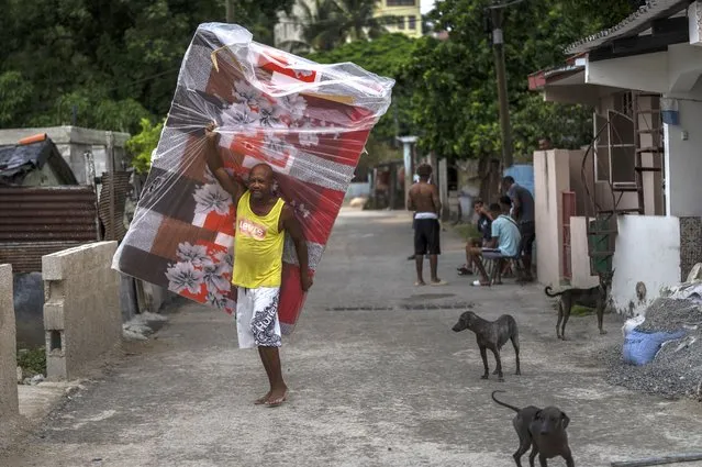A resident of El Fanguito neighborhood carries a mattress in preparation for the arrival of Hurricane Ian, in Havana, Cuba, Monday, September 26, 2022. (Photo by Ramon Espinosa/AP Photo)