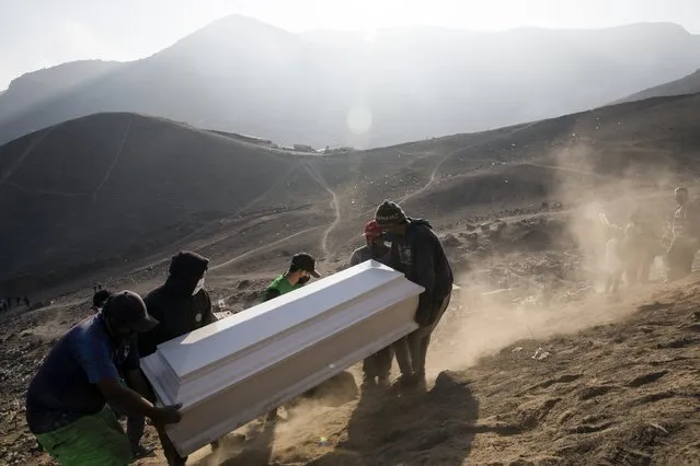 Cemetery workers carry the coffin of Jorge Luis Collahua, during his burial in the section of Nueva Esperanza cemetery reserved for COVID-19 cases, in the outskirts of Lima, Peru, Monday, June 1, 2020. Collahua's family did not want to talk about whether he died of the coronavirus. (Photo by Rodrigo Abd/AP Photo)