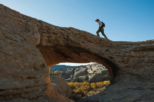 A man walks over a natural bridge at Butler Wash in Bears Ears National Monument near Blanding, Utah, October 27, 2017. (Photo by Andrew Cullen/Reuters)