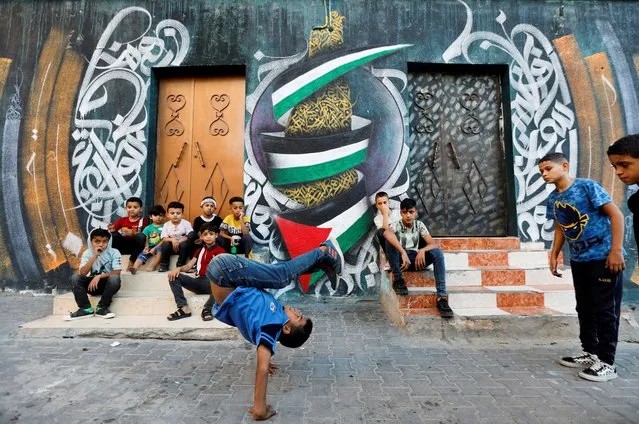 A Palestinian boy performs breakdancing on the street in Nusseirat refugee camp in central Gaza Strip on October 14, 2022. (Photo by Ibraheem Abu Mustafa/Reuters)