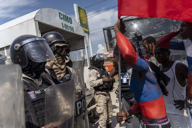 A protester taunts police officers during Jean-Jacques Dessalines Day in Port-au-Prince, Haiti, October 17, 2022. People are protesting the Prime Minister and Americans as the nation celebrates the 216th anniversary of the assassination of Dessalines, Haitian independence hero and founding father. (Photo by Richard Pierrin/AFP Photo)