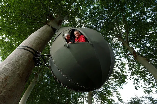 Guests pose a they sit inside a tear drop-shaped tent hanging from a tree created by Dutch artist Dre Wapenaar, offering an unusual accommodation for tourists in the Belgian countryside, near Borgloon, Belgium, July 7, 2020. (Photo by Francois Lenoir/Reuters)