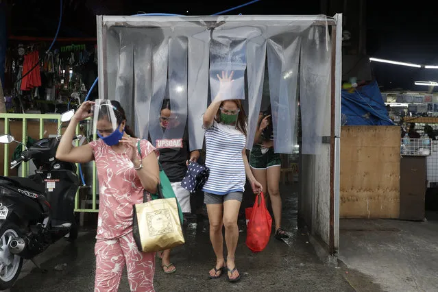 Women exit from a disinfecting area after buying food at a public market in preparation for stricter lockdown measures in Quezon city, Philippines on Monday, August 3, 2020. Philippine President Rodrigo Duterte is reimposing a moderate lockdown in the capital and outlying provinces after medical groups appealed for the move as coronavirus infections surge alarmingly. (Photo by Aaron Favila/AP Photo)