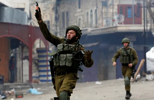 An Israeli soldier hurls a sound grenade at Palestinian demonstrators during clashes at a protest against U.S. President Donald Trump's decision to recognise Jerusalem as the capital of Israel, in the West Bank city of Hebron, December 29, 2017. (Photo by Mussa Qawasma/Reuters)