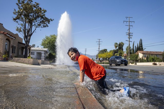 A boy plays in water from a broken fire hydrant in Rosemead, California on Saturday, May 10, 2025, seeking relief as spring heat breaks temperature records across the Southland. (Photo by Ringo Chiu/ZUMA Press Wire/Rex Features/Shutterstock)