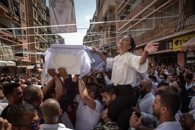 The sister (R) of 23-year-old firefighter Ralph Malahi who was killed in the August 4, Beirut port explosion, reacts while his coffin is carried by friends and relatives during his funeral on August 15, 2020 in Beirut, Lebanon. The explosion at Beirut's port last week killed over 200 people, injured thousands, and upended countless lives. There has been little visible support from government agencies to help residents clear debris and help the displaced, although scores of volunteers from around Lebanon have descended on the city to help clean. (Photo by Chris McGrath/Getty Images)