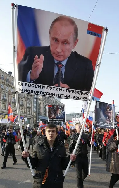 A man carries a portrait of Russia's President Vladimir Putin as he attends a demonstration on National Unity Day in Moscow November 4, 2014. The sign reads: “I want in to the USSR”. (Photo by Sergei Karpukhin/Reuters)
