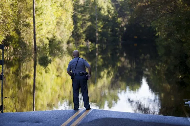 Horry County police officer Jeff Helfinstine patrols the edge of flood waters along Lee's Landing Circle in Conway, South Carolina October 7, 2015. Rescuers searched early Wednesday for two people missing in floodwaters in South Carolina, while authorities urged residents in hundreds of homes to seek higher ground. (Photo by Randall Hill/Reuters)