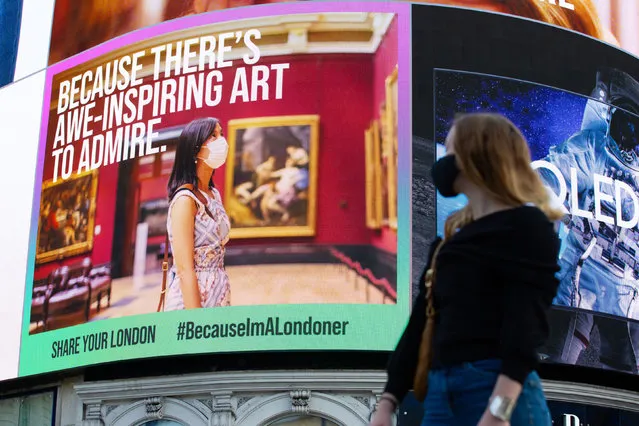 A woman looks at a digital billboard at Piccadilly Circus in London on August 31, 2020 promoting the #BecauseImALondoner campaign, which aims to encourage residents to safely explore their areas and support local businesses as part of Covid recovery efforts. (Photo by David Parry/PA Wire Press Association)