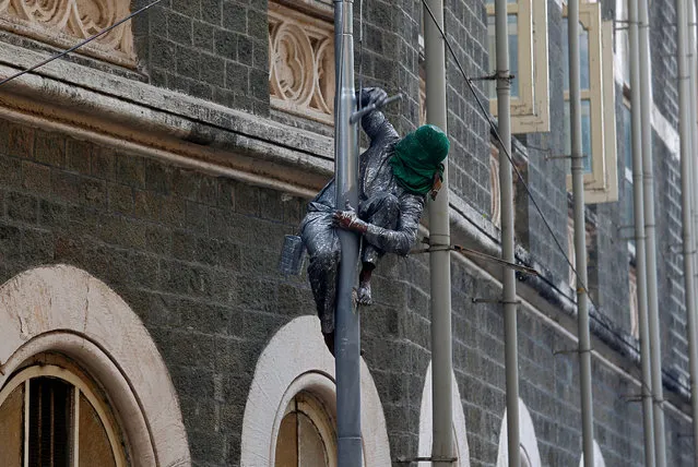 A worker paints a lamp post on a street in Mumbai, January 9, 2018. (Photo by Shailesh Andrade/Reuters)