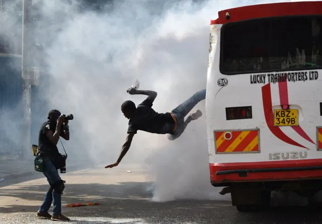 A supporter of Kenyan opposition leader Raila Odinga of the National Super Alliance (NASA) coalition jumps from a bus after riot police fired teargas canisters to disperse them after his swearing-in ceremony in Nairobi, Kenya January 30, 2018. (Photo by Isaac Biosse/Reuters)