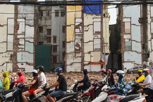 Motorists ride their vehicles past a residential area being cleared for road expansion in Hanoi on August 25, 2020. (Photo by Nhac Nguyen/AFP Photo)