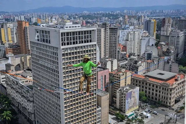 Brazilian highliner Rafael Bridi performs on a slackline 114 meters high and 510 meters long, crossing the entire Vale do Anhangabau, as part of the 469th anniversary of the city of Sao Paulo, Brazil on January 25, 2023. Bridi broke his own urban distance record for the Americas, according to the International Slackline Association. (Photo by Nelson Almeida/AFP Photo)