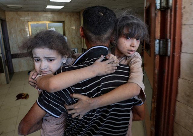 A Palestinian carries children as wounded Palestinians receive treatment at Al-Aqsa Martyrs Hospital, after an Israeli airstrike on a house, in Deir al-Balah, central Gaza Strip on July 8, 2025. (Photo by Ramadan Abed/Reuters)