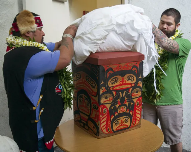 Tlingit Tribe members from Klawock, Alaska Jonathan Rowan, left, and Lawrence Armour unveil a carved Alaskan storage box at the Honolulu Museum of Arts, Thursday, October 22, 2015, in Honolulu. The box was a thank you gift for the return of their totem pole. (Photo by Marco Garcia/AP Photo)