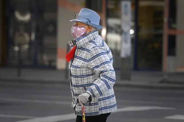 A woman wears a face mask for protection against COVID-19 infection while crossing a street in Bucharest, Tuesday, October 20, 2020. Local authorities imposed the use of face masks in all public spaces, indoors and outdoors, closed schools, restaurants, theatres and cinemas after the rate of COVID-19 infections went above 3 cases per 1000 inhabitants in the Romanian capital Bucharest. (Photo by Andreea Alexandru/AP Photo)