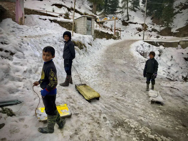 Children wait for tourists to give them snow ride on their wooden planks, in Narkanda, in the Indian state of Himachal Pradesh, Friday, February 10, 2023. (Photo by Manish Swarup/AP Photo)