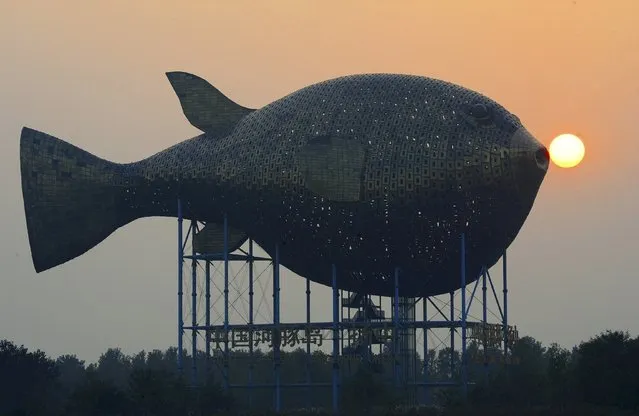 The sun sets behind a viewing tower in the shape of a giant puffer fish, on the banks of a river in Yangzhong county, Jiangsu province, China, October 23, 2015. (Photo by Reuters/Stringer)