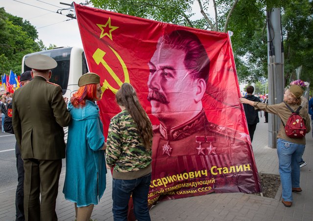Moldovans stand neat a flag depicting a portrait of former Soviet leader Joseph Stalin as they take part during a march downtown Chisinau to celebrate the Victory Day on May 9, 2024. Couple thousand people gather in the capital city of Moldova in a march celebrating the victory of the soviet army against the fascism on WWII, an important day for the former states members of Soviet Union. (Photo by Elena Covalenco/AFP Photo)