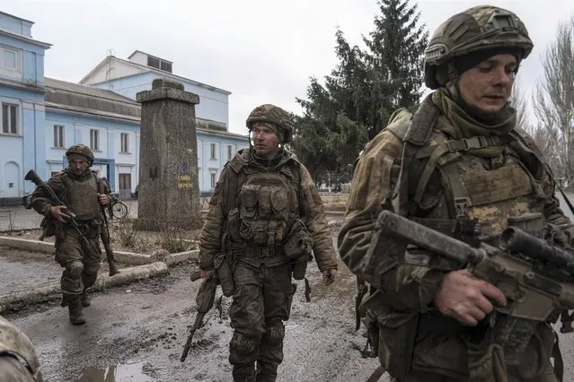 Ukrainian servicemen walk on a street as he just come back from tranches of Bakhmut in Chasiv Yar, Ukraine, Wednesday, March 8, 2023. (Photo by Evgeniy Maloletka/AP Photo)