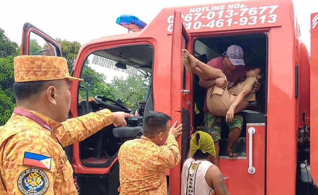 This handout photo taken on October 10, 2025, and made available through the courtesy of the Facebook page of the Bureau of Fire Protection Region 11 shows a member of the Bureau Fire Protection evacuating a resident in Baganga town, Davao Oriental province, in southern island of Minadanao, after a 7.4-magnitude struck the province. A powerful magnitude-7.4 earthquake struck off the southern Philippines on October 10, 2025, killing at least six people and triggering regional tsunami warnings that were later lifted. (Photo by Handout/Bureau of Fire Protection Region 11/AFP Photo)