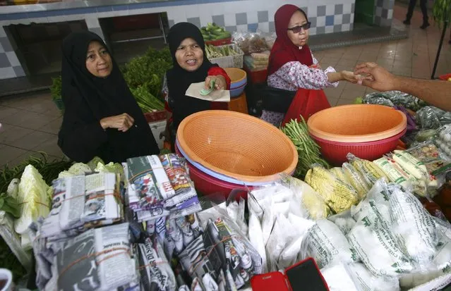 Women pay their bills at a wet market in Shah Alam outside Kuala Lumpur, Malaysia in this January 22, 2014 file photo. (Photo by Samsul Said/Reuters)