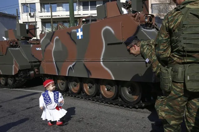 A little boy dressed as Evzonas walks in front of military vehicles during a military parade marking Greece's Independence Day outside the Greek Parliament building in Athens, Greece, 25 March 2023. The national holiday on 25 March marks the start of Greece's 1821 war of independence against the 400-year Ottoman rule. (Photo by Yannis Kolesidis/EPA)